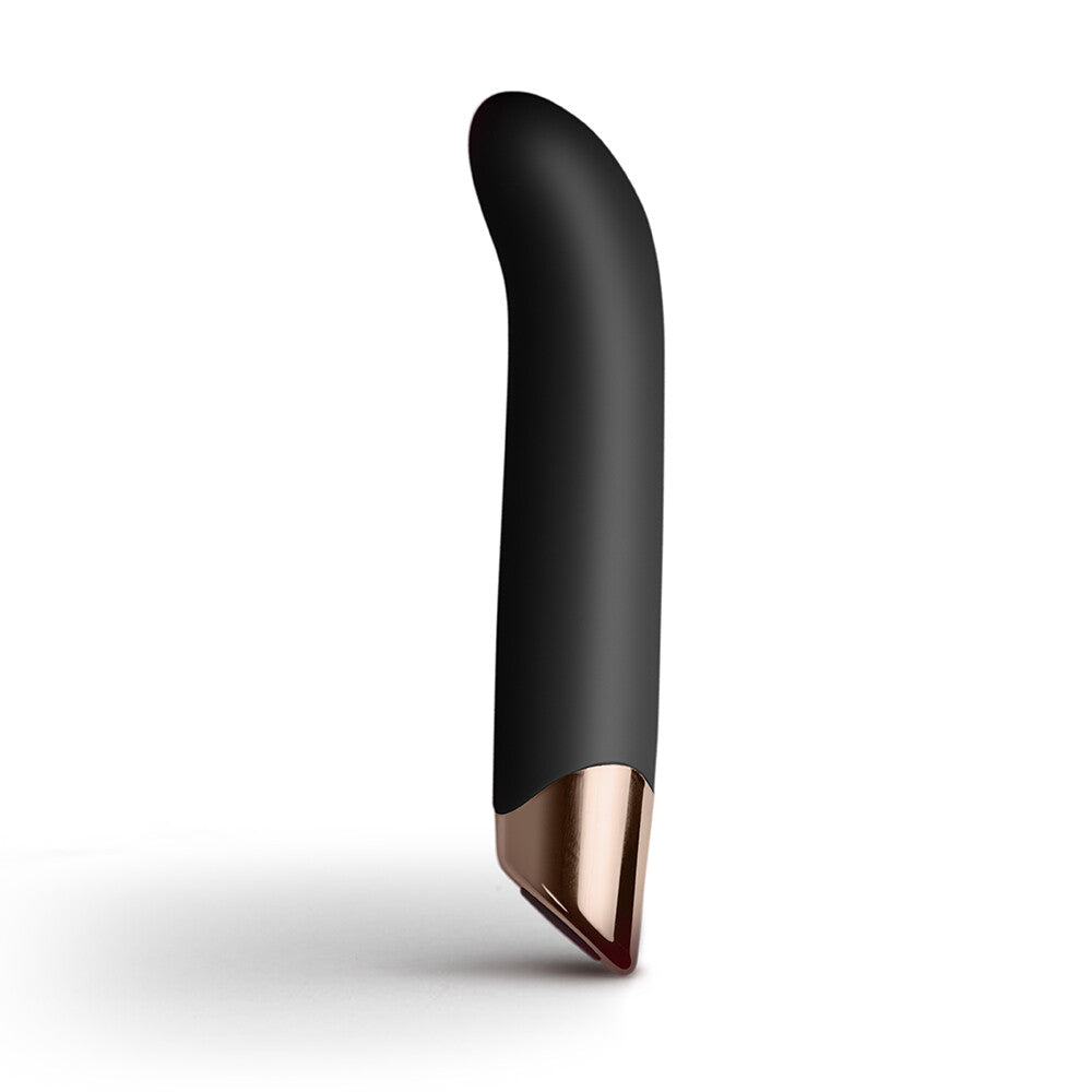 A sleek, black G-spot vibrator with an ergonomic angled tip, resting on a rock, with a branch in the background.
