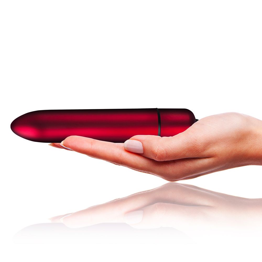 A red, bullet-shaped vibrator being held in a hand, showcasing its compact size and smooth surface.
