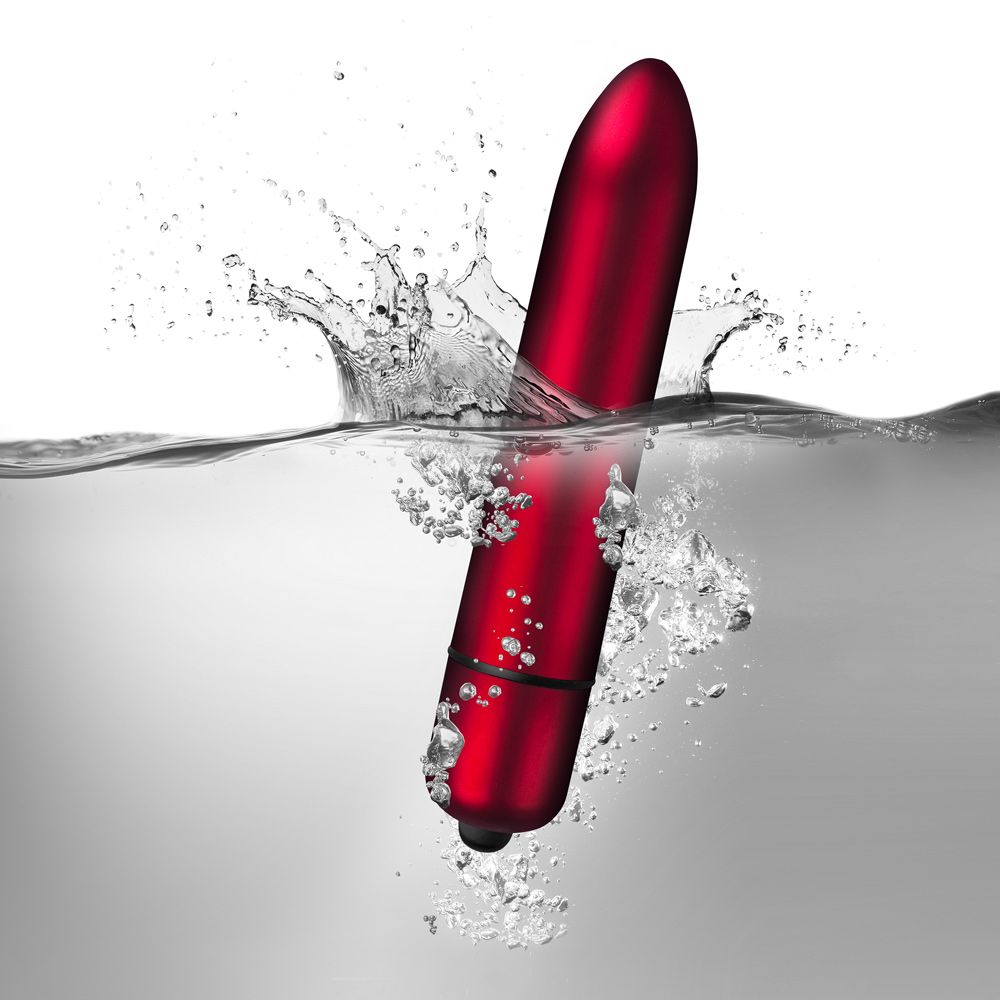A red, bullet-shaped vibrator being held in a hand, showcasing its compact size and smooth surface.