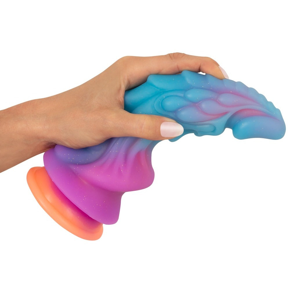 Hand holding a colorful squishy toy with a gradient from blue to pink to orange on a white background.