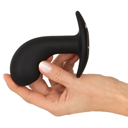 Black silicone butt plug held in a hand on a white background