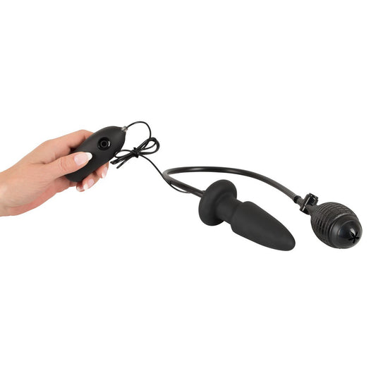 Black electronic device with a cable, held by a hand on a white background