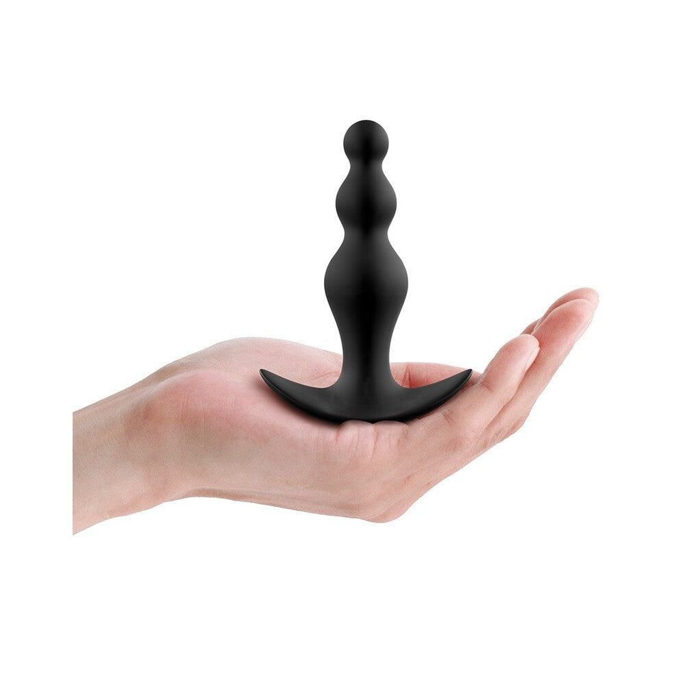 Black decorative item held in a hand on a white background