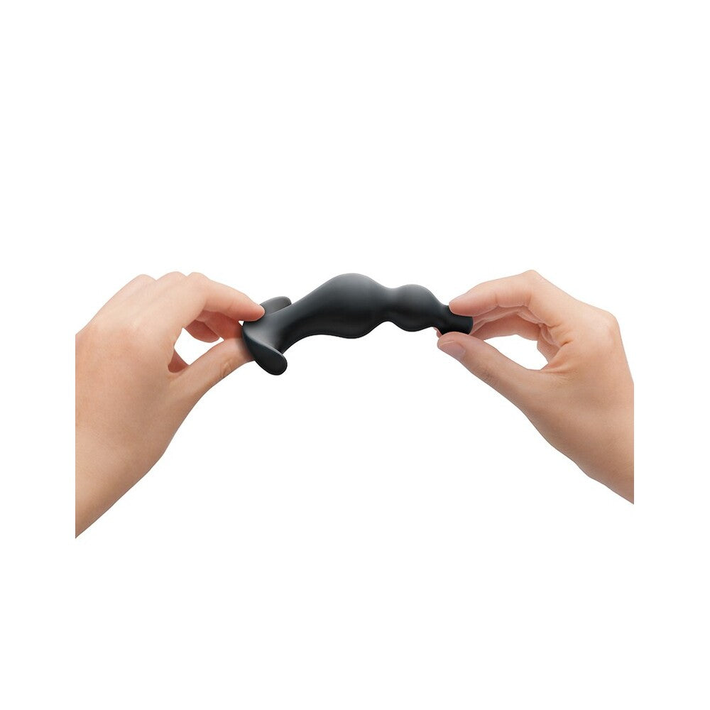 Black flexible object being held and twisted by two hands on a white background