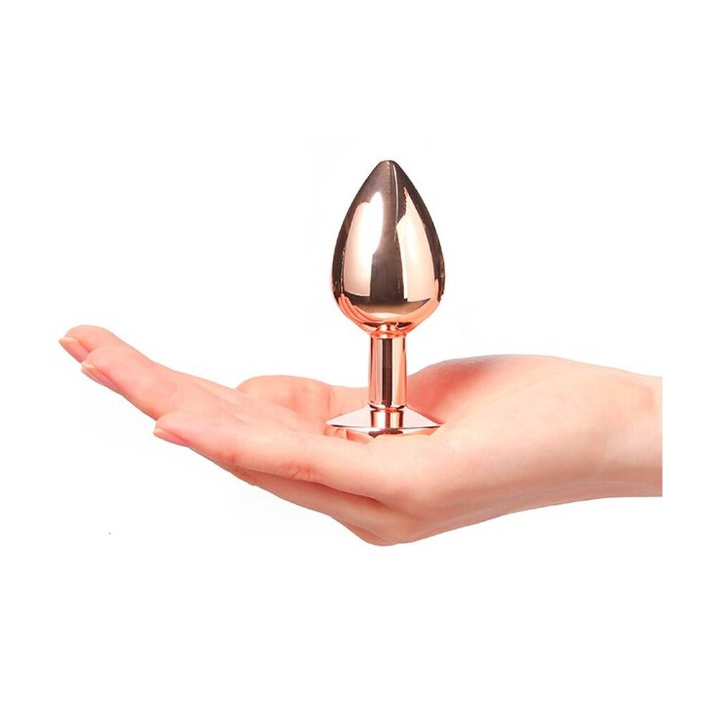 Rose gold metal butt plug held in a hand on a white background