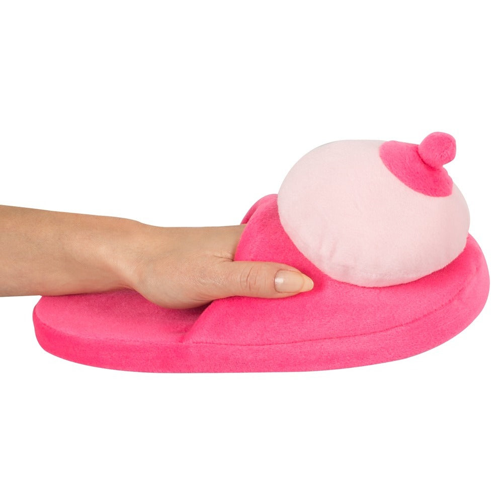 A pair of pink slippers made of fur fabric designed with boob-shaped tops.