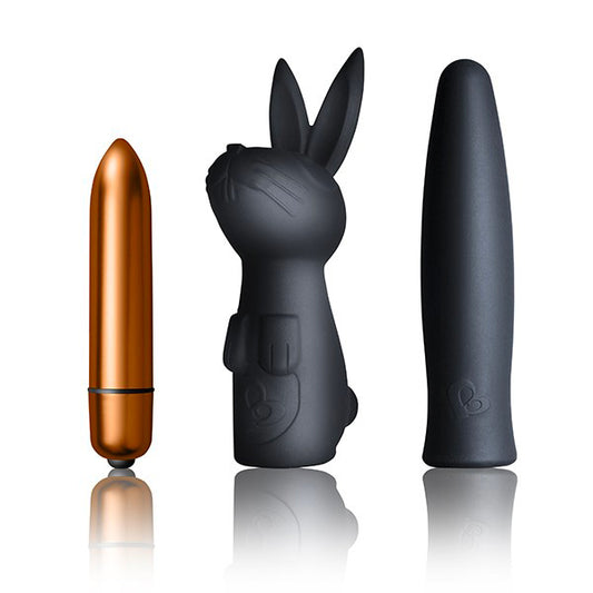The image shows three black sexual wellness products. From left to right, there is a small cylindrical vibrator, a silicone bunny-shaped vibrator, and a larger, sleeker vibrator.