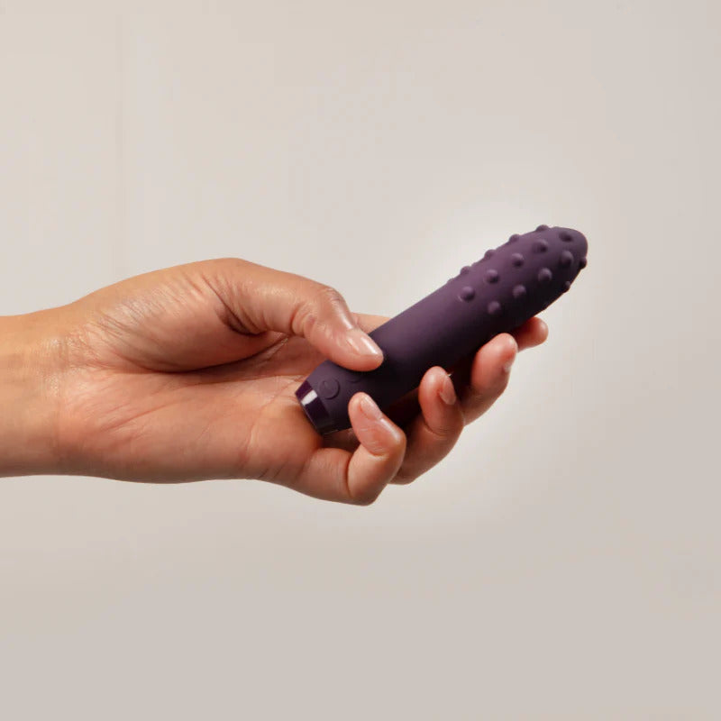A purple, bullet-shaped vibrator with a textured, multi-surfaced tip and control buttons near the base.