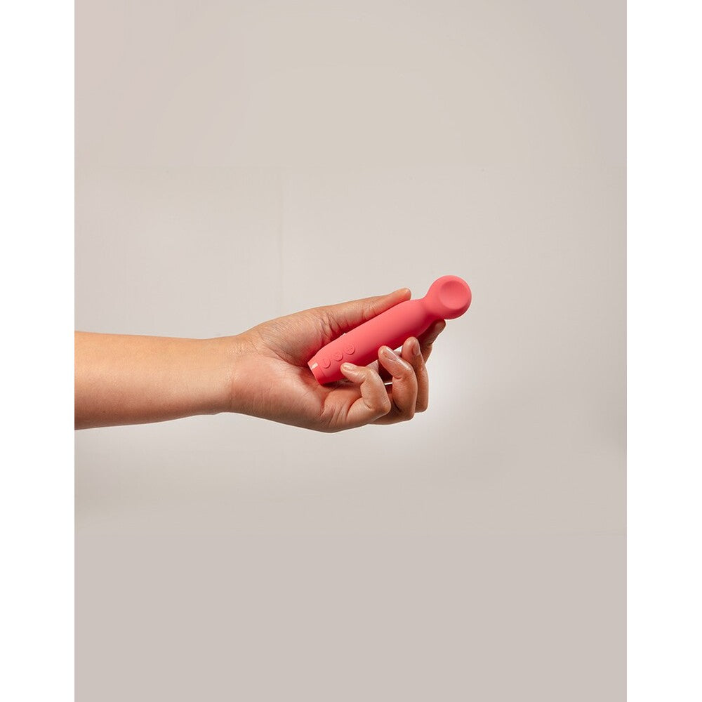 A hand holding a red, bullet-shaped vibrator with a smooth, rounded tip.