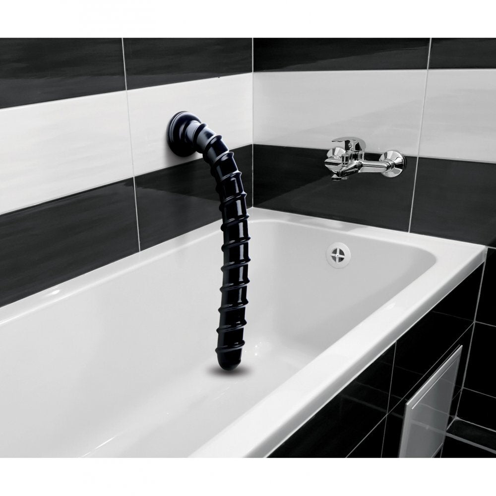Black industrial-style faucet mounted on a white bathtub with black tiled walls.
