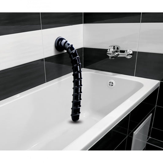 Black industrial-style faucet mounted on a white bathtub with black tiled walls.