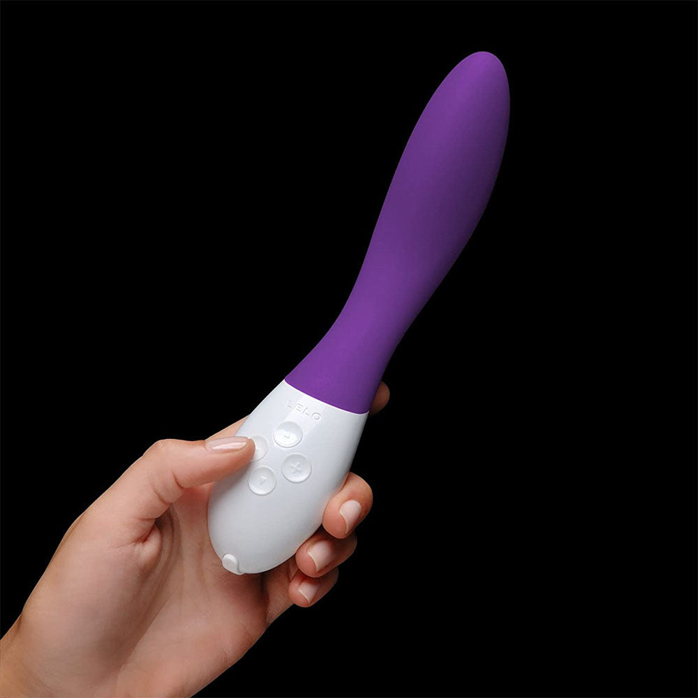 Purple and white electronic device held in a hand against a black background