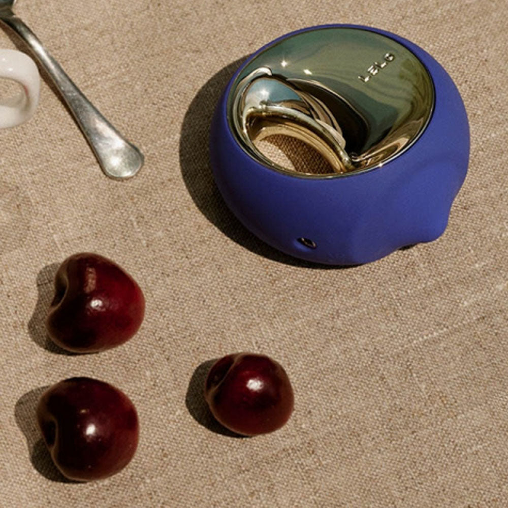 Blue cocktail shaker with cherries on a textured surface