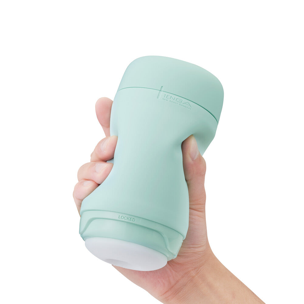 Hand holding a light green handheld device against a white background