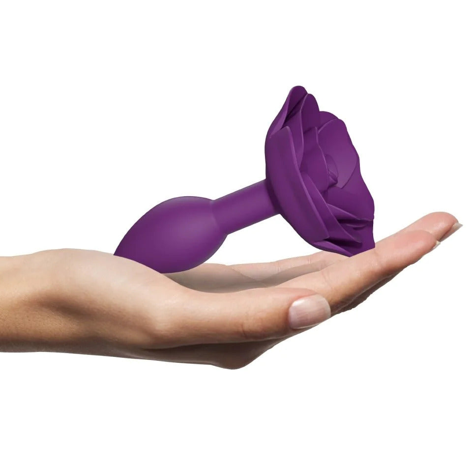 Purple flower-shaped object held in a hand on a white background