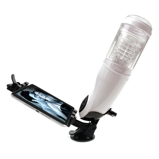 A white, cylindrical device connected to a black base which holds a mobile phone. The device appears to be a masturbator designed for hands-free use.