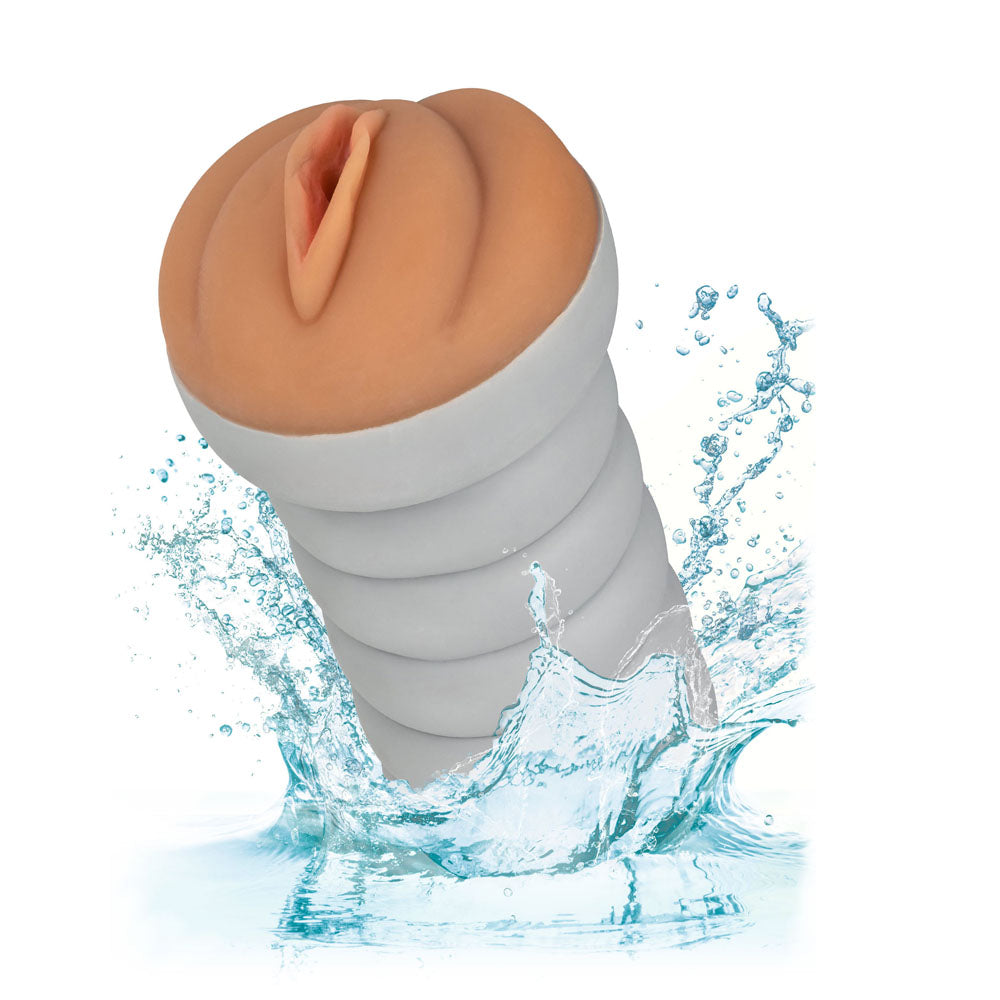 A brown masturbator designed to resemble a female genitalia, with a ribbed and tight structure, depicted with water splashing around indicating its waterproof feature.