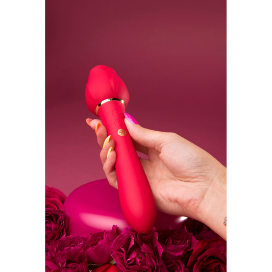 A red dual-ended vibrator being held, with one end insertable and the other featuring a flickering tongue for clitoral stimulation.