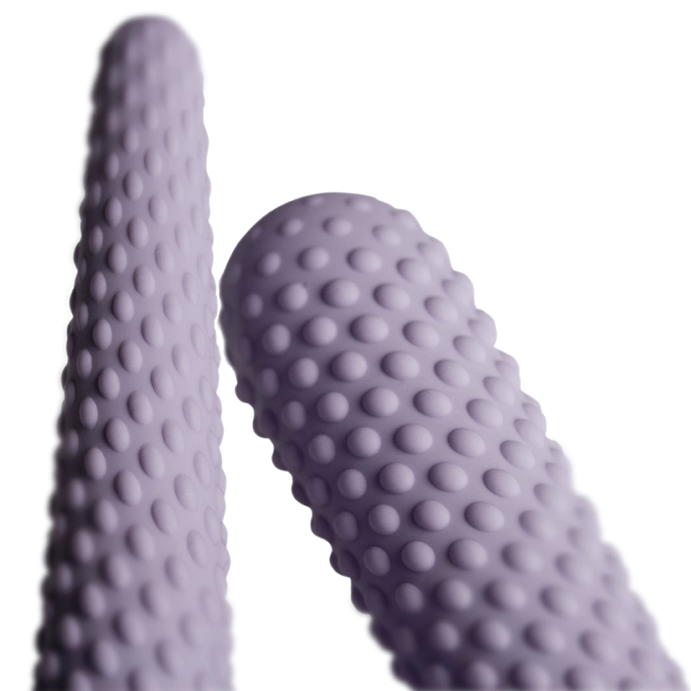 A set of three purple silicone dilators of varying sizes, each with a textured surface.