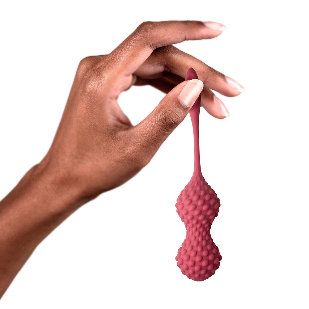 A pair of pink silicone kegels with sensory nodules and retrieval tails, designed for ergonomic insertion and stimulation.