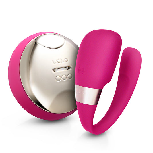 A pink couples massager with a sleek, ergonomic design. The product is shown with a remote control that has a metallic finish.