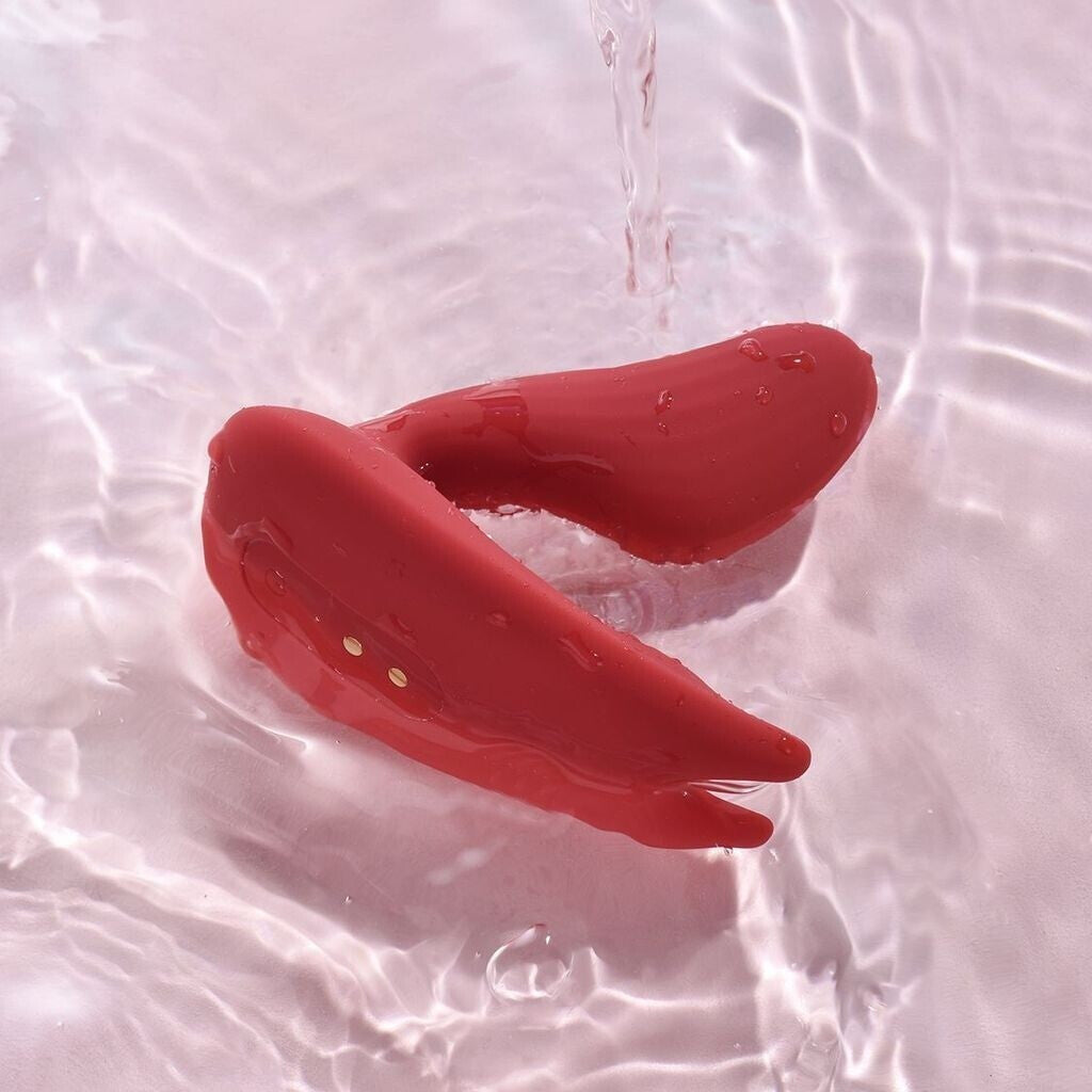 Red rubber duck floating on water with ripples.