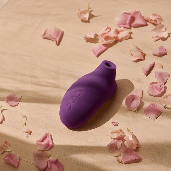 Purple silicone product on a beige surface with pink flower petals
