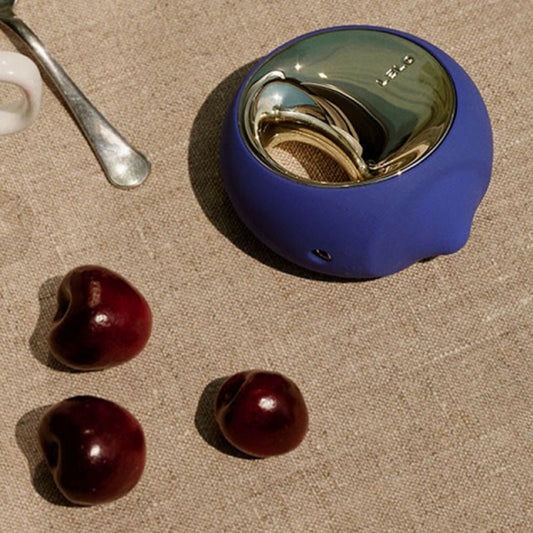 Blue cocktail shaker with cherries on a textured surface