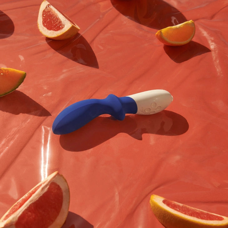 Blue and white tool on a red surface with sliced oranges and grapefruits.