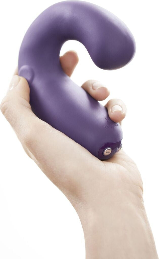 Purple handheld massager held in a hand against a white background